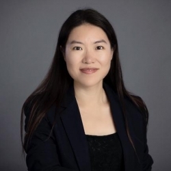 Shuoyuan He, headshot of woman with long black hair wearing dark suit jacket and blouse